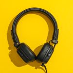 Headphones on color background, space for text